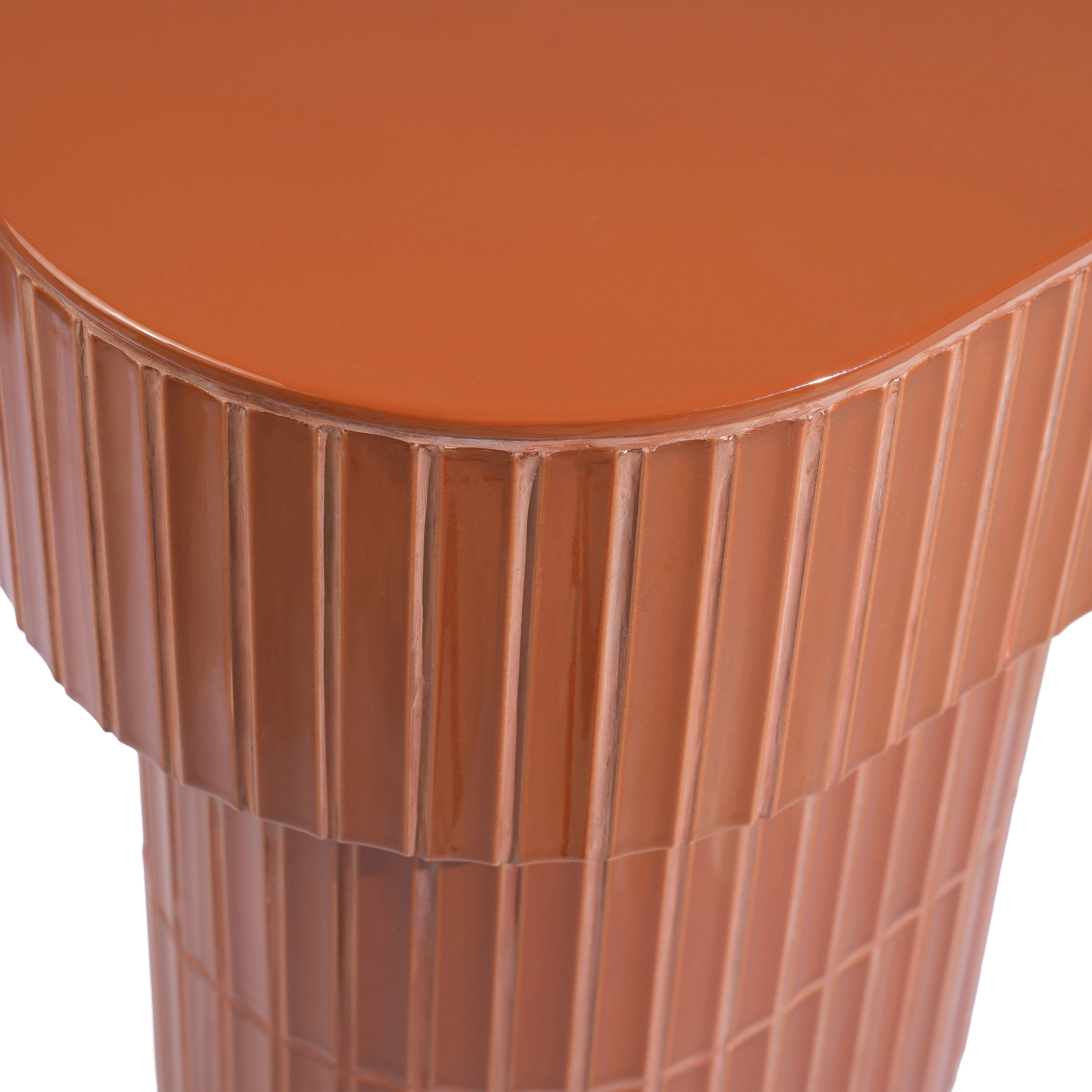 Close-up of a brown-colored side table showing the smooth rounded top and tiled pedestal base.